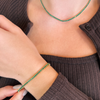 Person wearing a green beaded bracelet and necklace with a brown ribbed sweater.