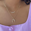 Necklace with a horseshoe pendant worn by a person against a pink background