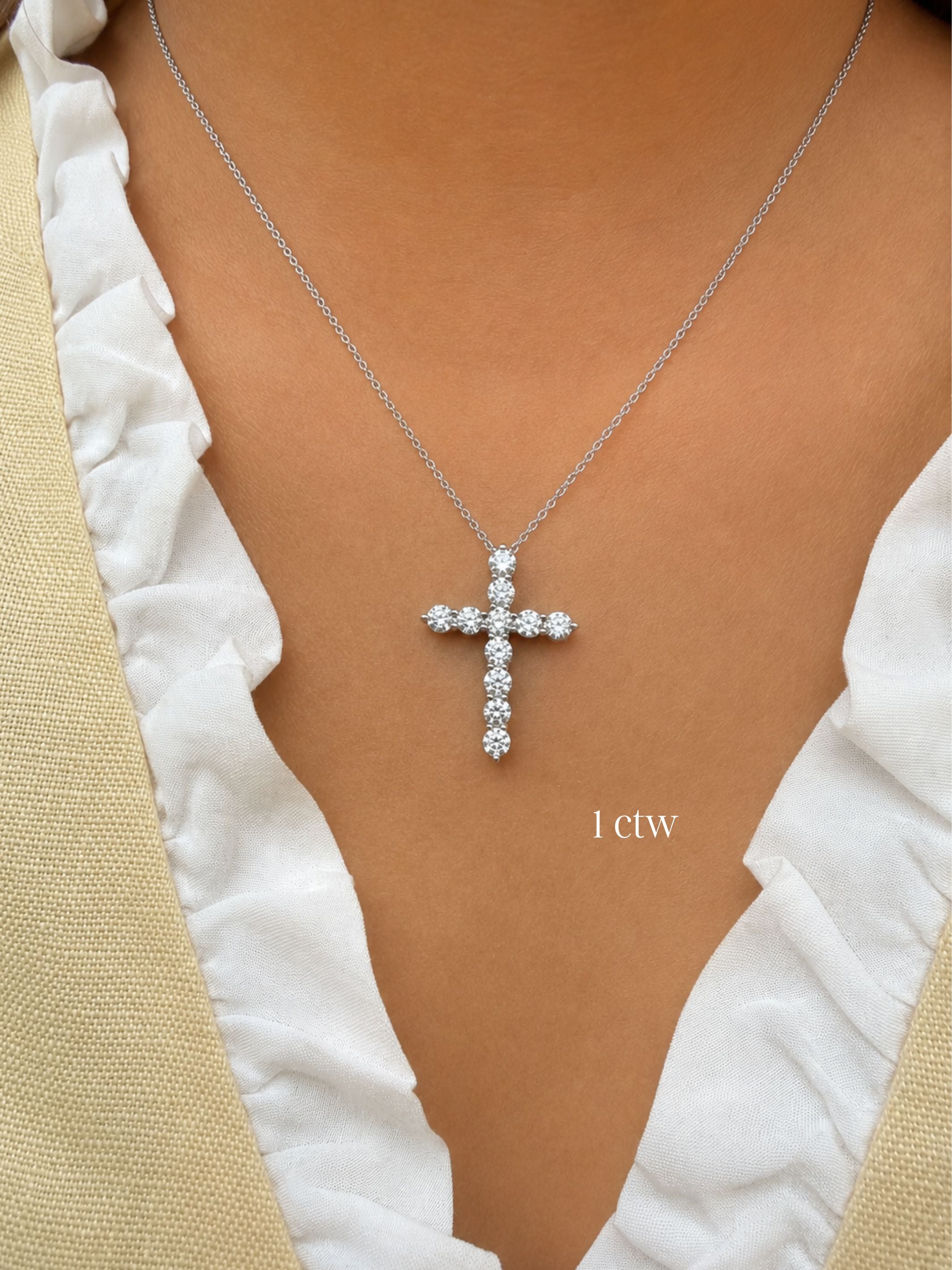 1ctw Diamond cross necklace on a person wearing a white top with beige sleeves.