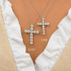 Two white gold cross necklaces with diamond accents on a person wearing a white garment.