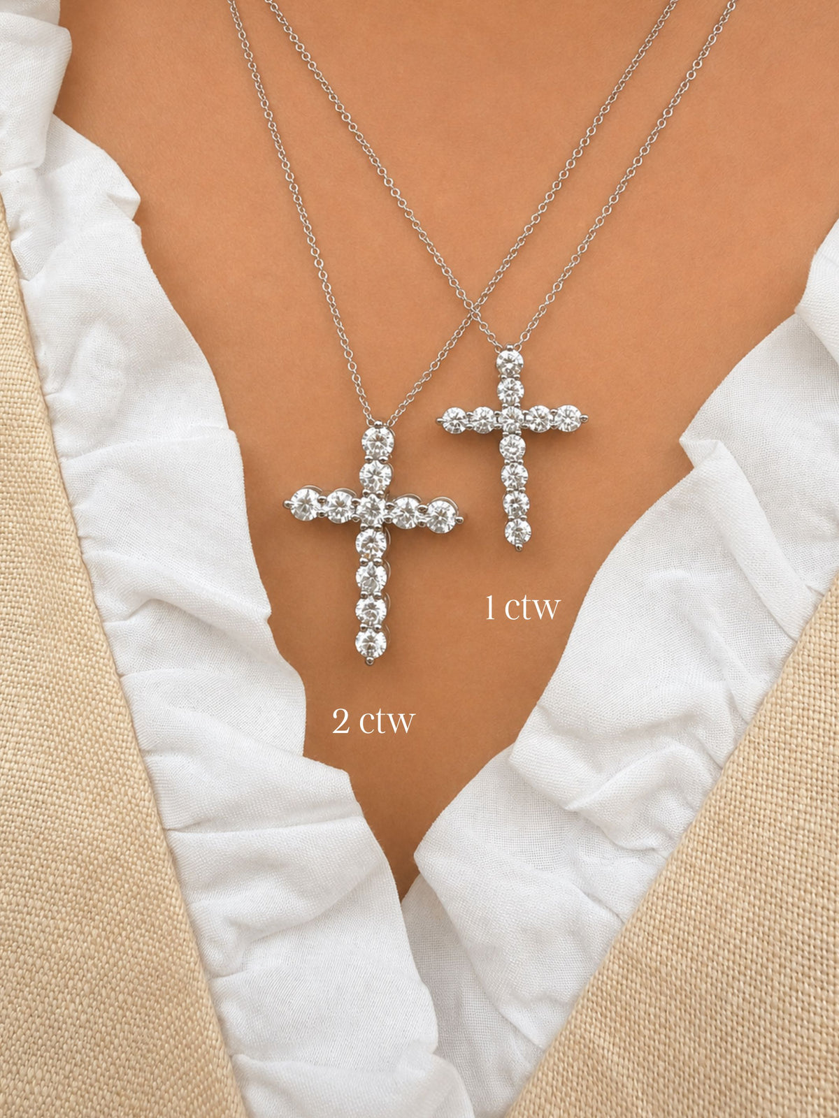 Two white gold cross necklaces with diamond accents on a person wearing a white garment.