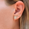 Diamond flower earrings paired with diamond v earrings, diamond huggie, and diamond mini stud on model ear