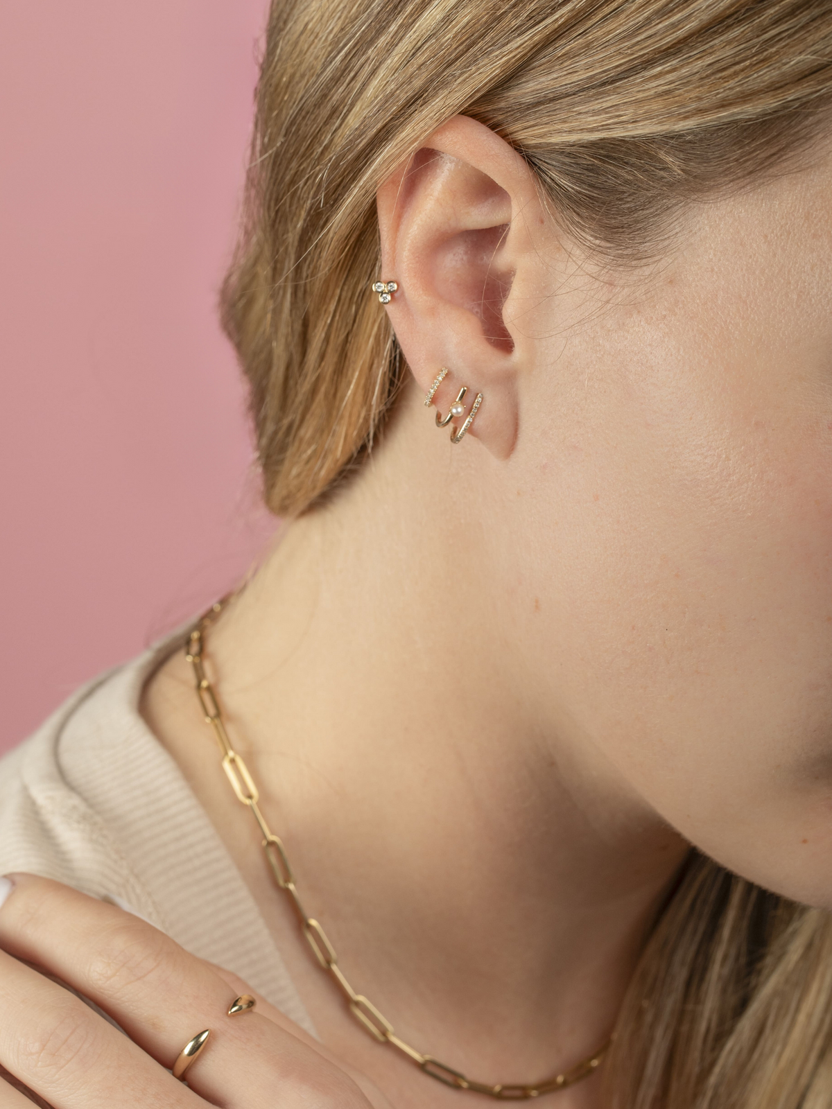 Double Bar pearl huggie earrings layered with a mini diamond huggie and a trio bezel earring