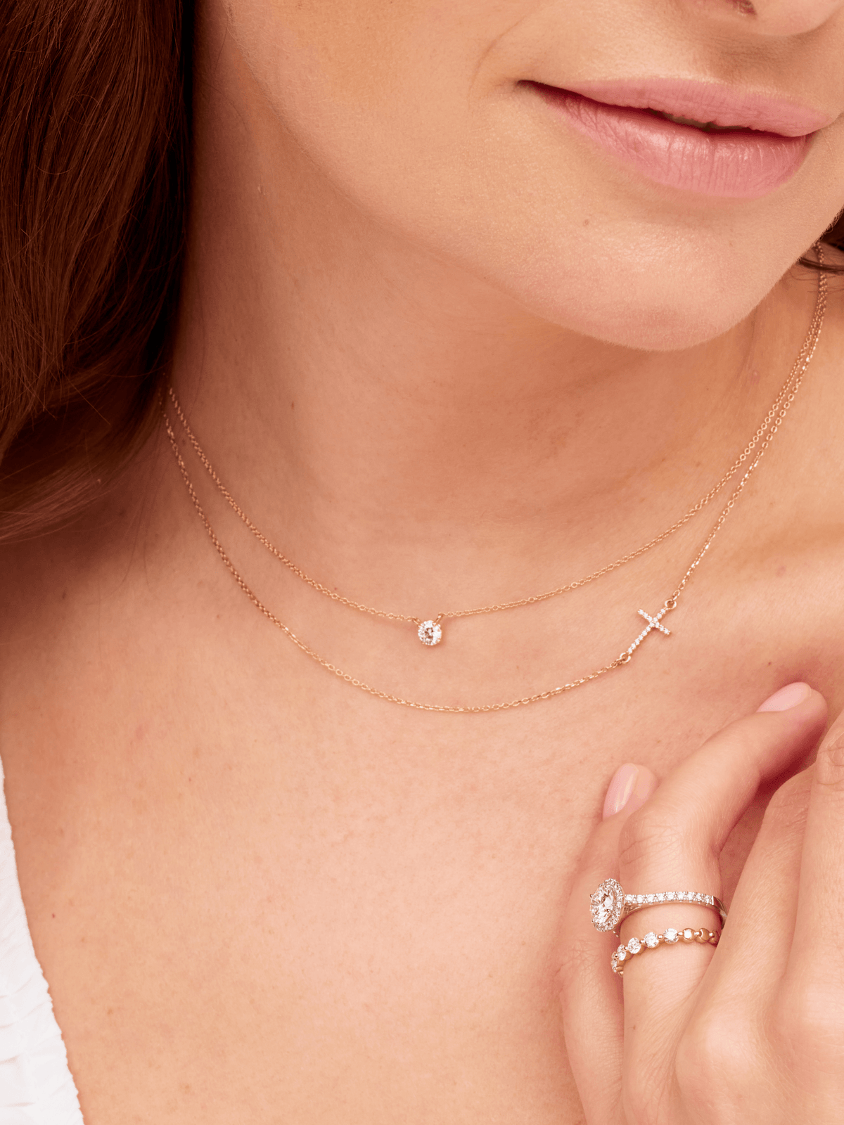 Round diamond necklace layered with gold diamond cross necklace