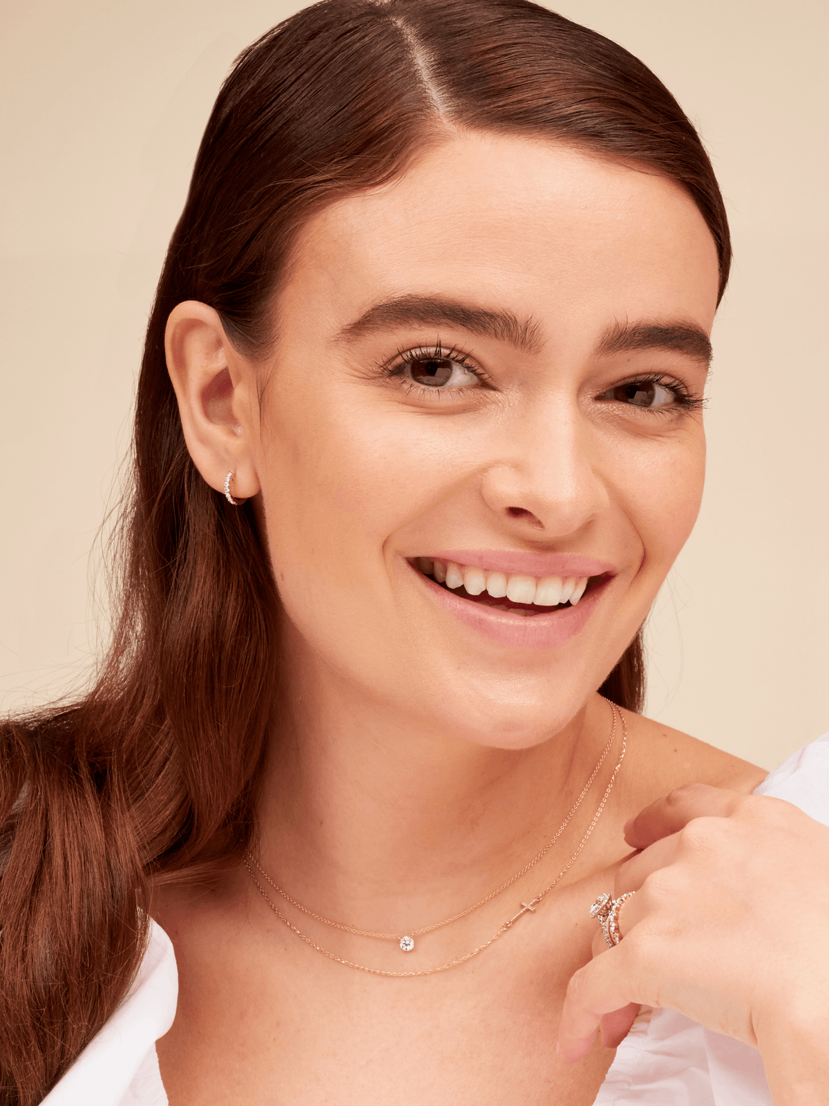 Round diamond necklace layered with gold diamond cross necklace