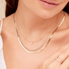 Round diamond pendant necklace layered with diamond tennis chain necklace and gold snake chain