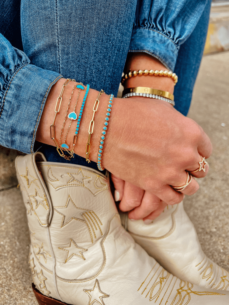 Turquoise tennis bracelet layered with gold paperclip chain bracelets, half turquoise half paperclip chain bracelet, turquoise enamel heart bracelet, and gold chain bracelet