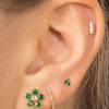 Emerald and diamond flower stud paired with diamond huggie, emerald trio stud, and diamond bar stud on model ear