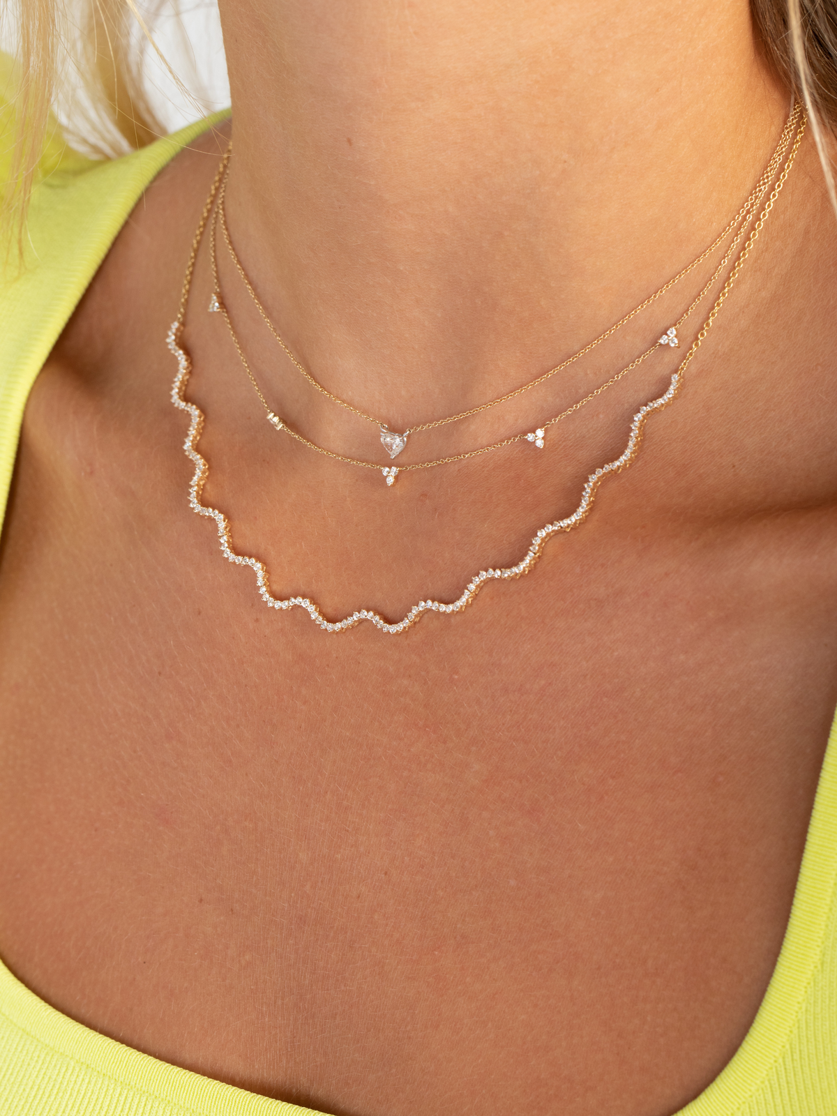 wave shaped diamond tennis necklace layered with a trio diamond layering necklace and a diamond heart necklace