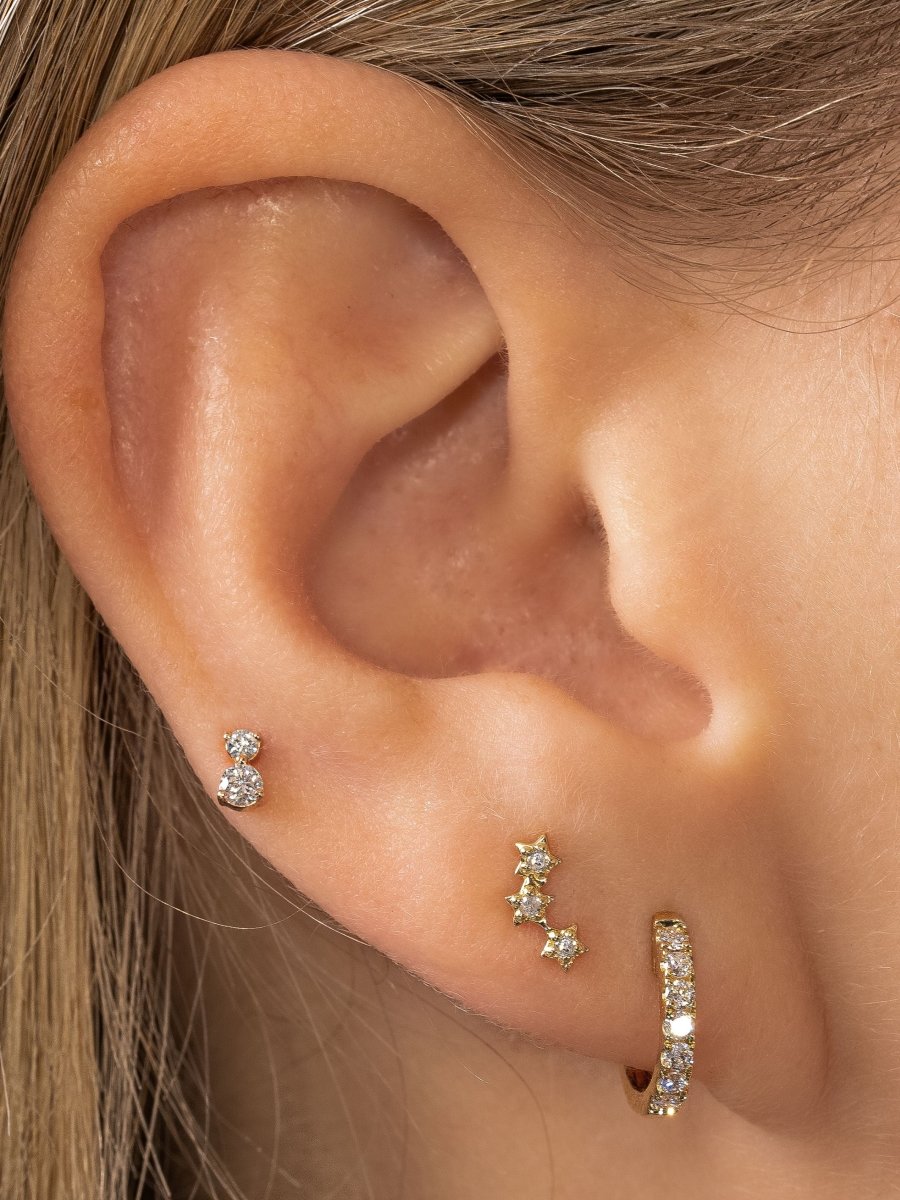 Diamond huggie paired with diamond star stud and tiny diamond stud on model ear