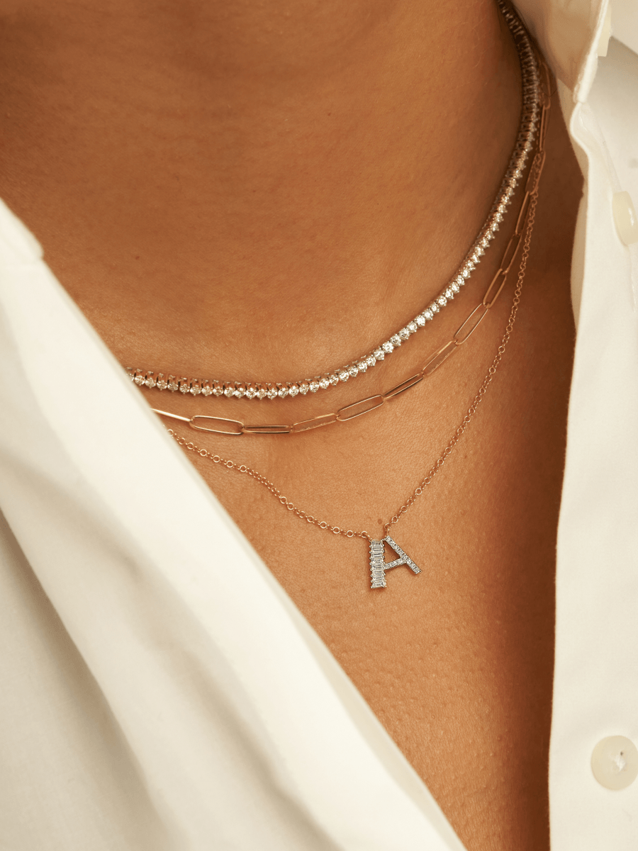 14K gold baguette diamond initial charm on dainty gold chain layered with thin gold paperclip chain and diamond tennis choker necklace