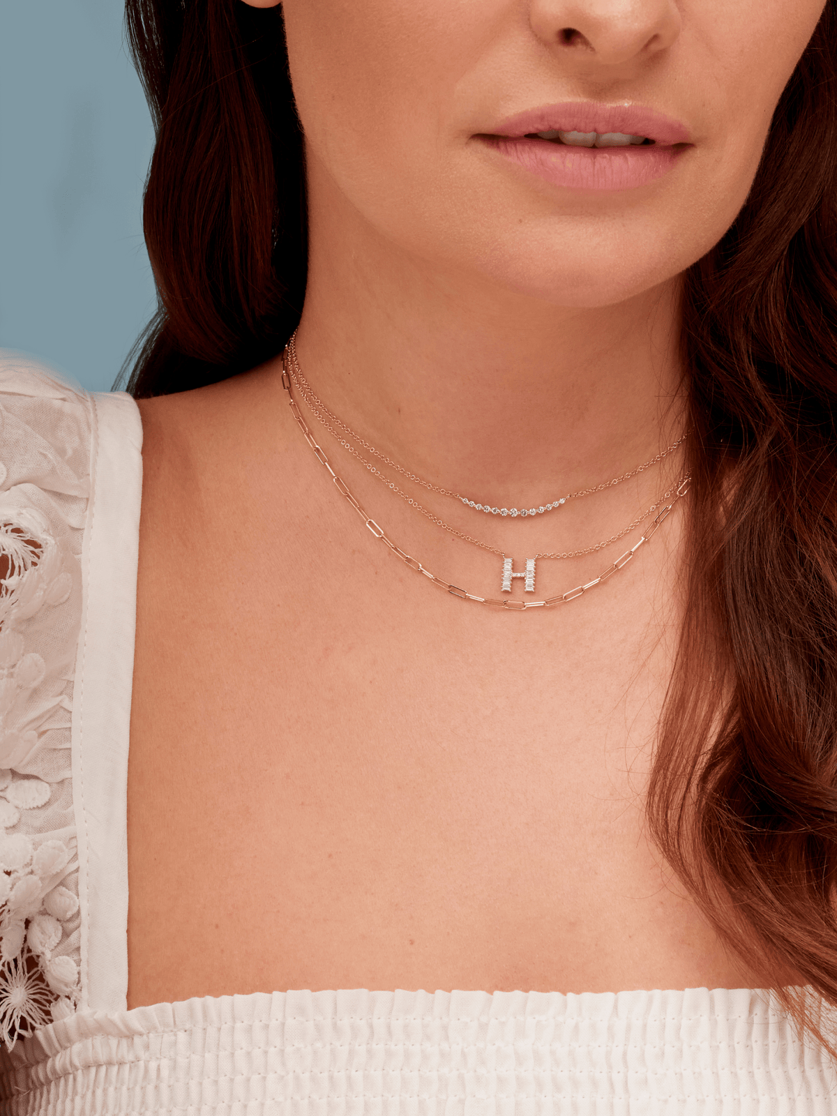 14K gold baguette diamond initial charm on dainty gold chain layered with dimaond chasing gold necklace and thin gold paperclip necklace