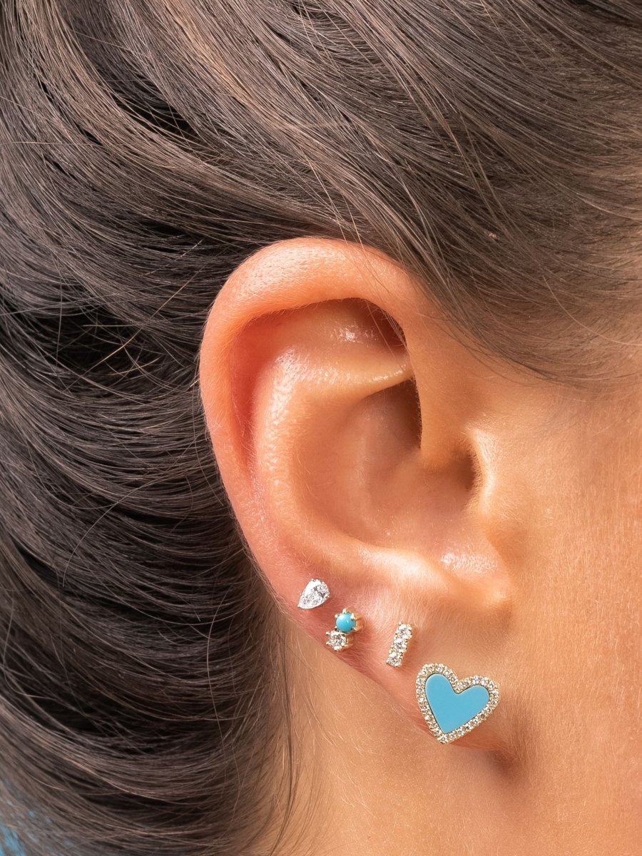 Diamond pear stud paired with turquoise and diamond stud, diamond bar stud, and turquoise and diamond heart stud on model ear