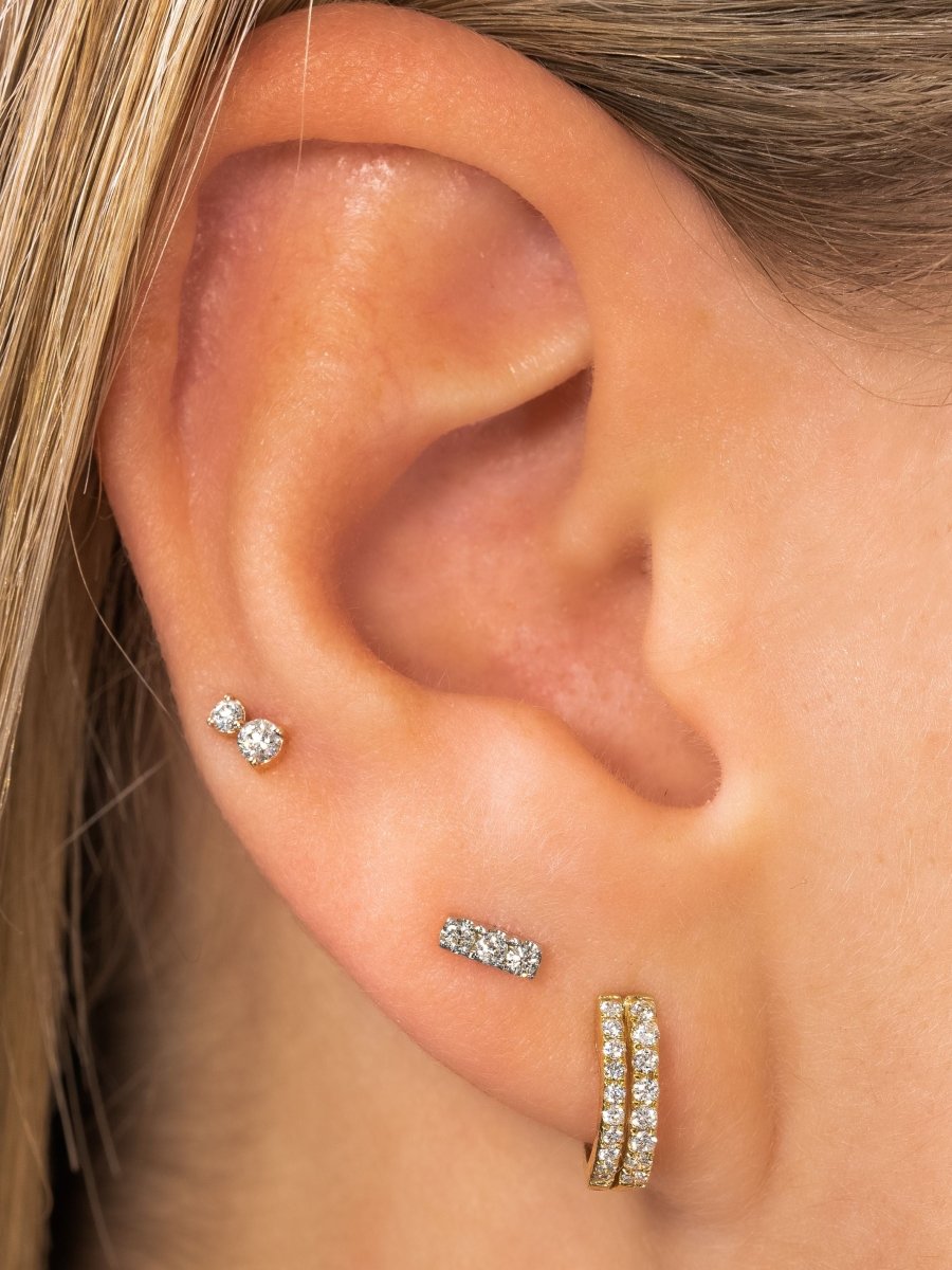 Tiny diamond stud paired with diamond bar stud and diamond huggie on model ear