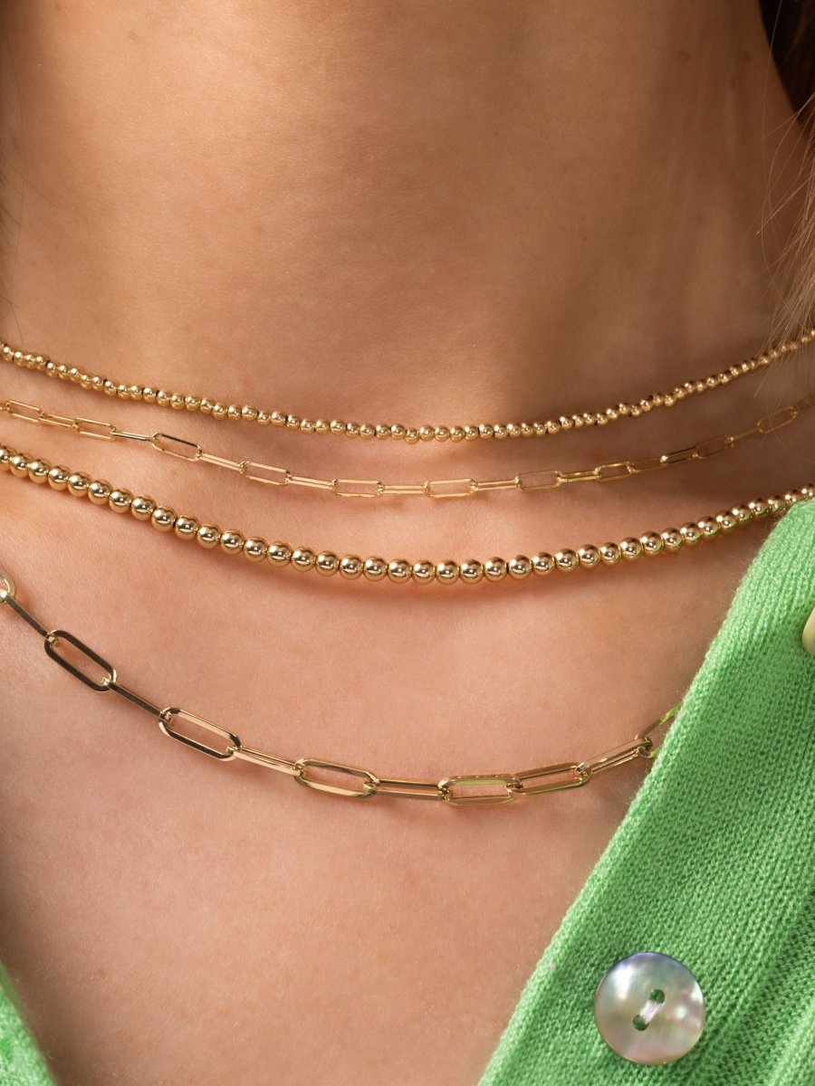 Gold choker necklaces layered with gold paperclip chains