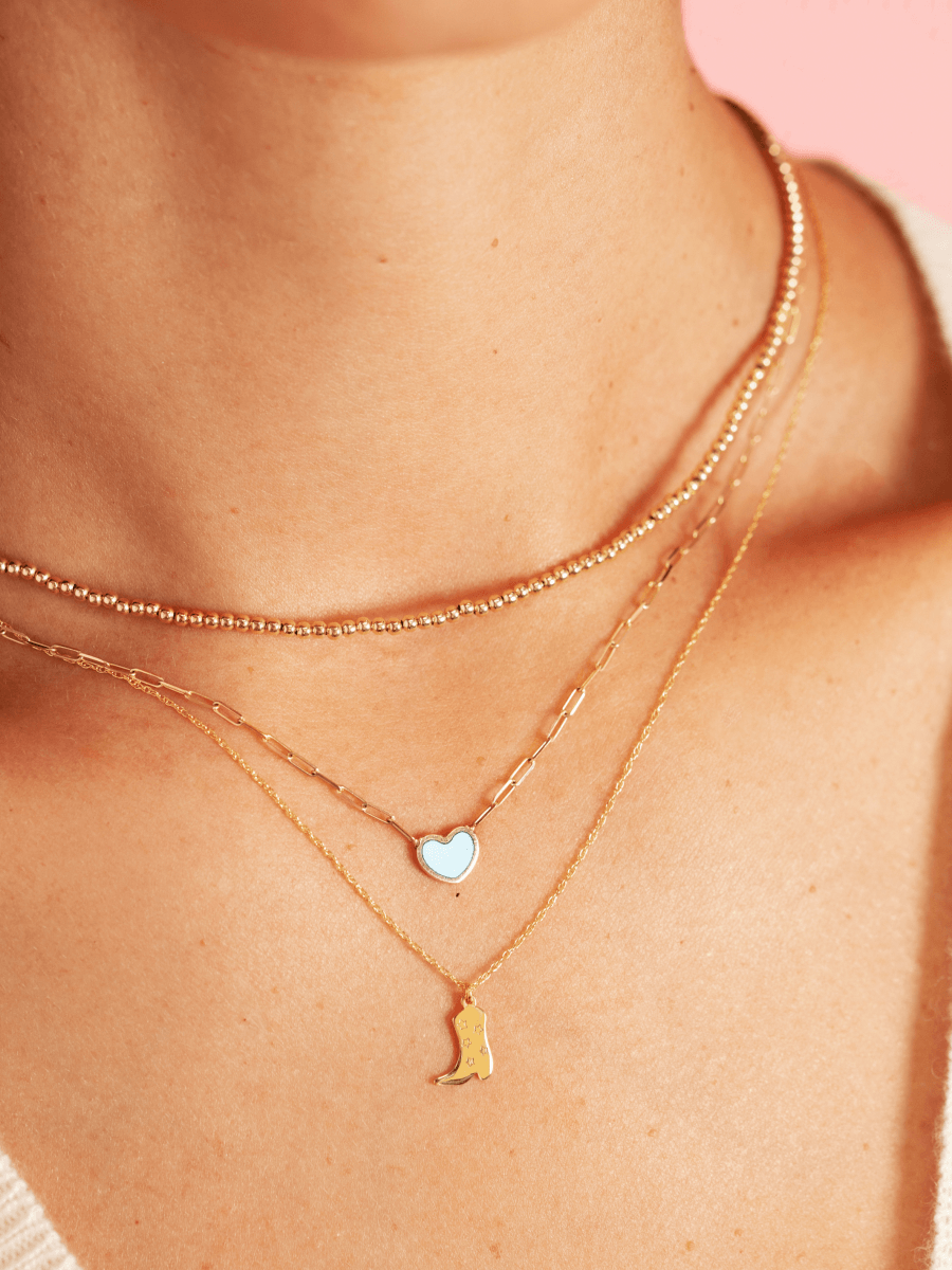 Thin gold choker layered with turquoise enamel heart necklace and enamel cowboy boot necklace