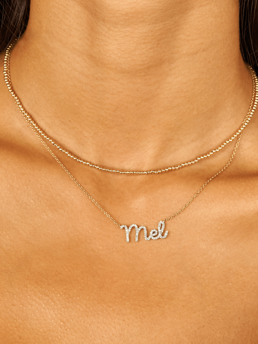 Gold choker necklace layered with diamond name necklace