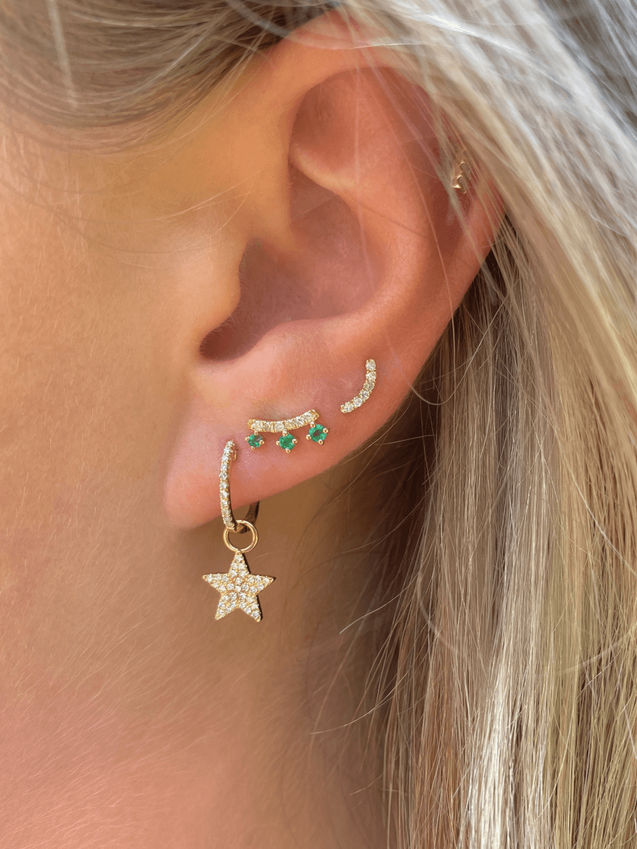 Emerald stud earrings paired with diamond star huggie and bridge diamond stud
