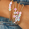 Name and initial bracelets with gold beads paired with simple gold beaded bracelet on model wrist