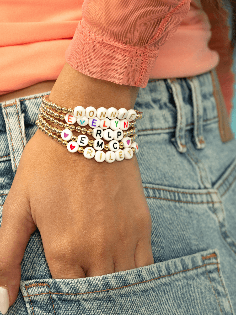 Name bracelets with gold beads on model wrist