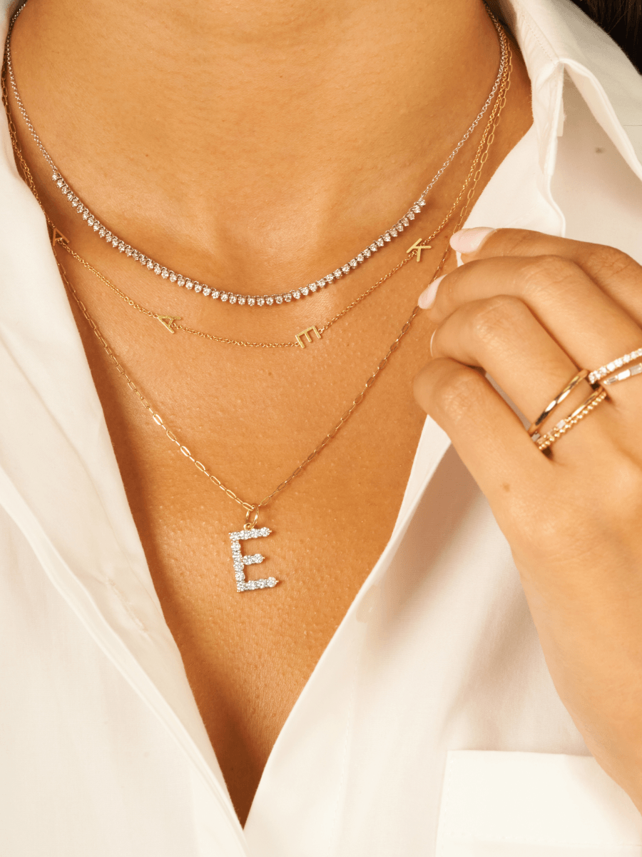 Dainty gold chain necklace with diamond initial charm layered with tennis chain necklace and gold initial necklace