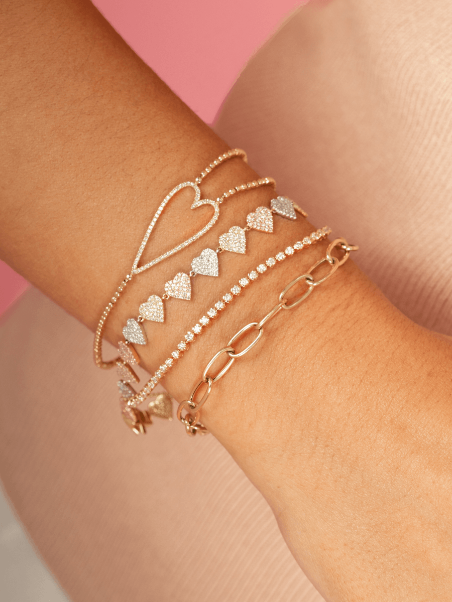Bezeled diamond tennis chain bracelet stacked with diamond open heart with gold beads bracelet, gold chain bracelet, and diamond heart bracelet