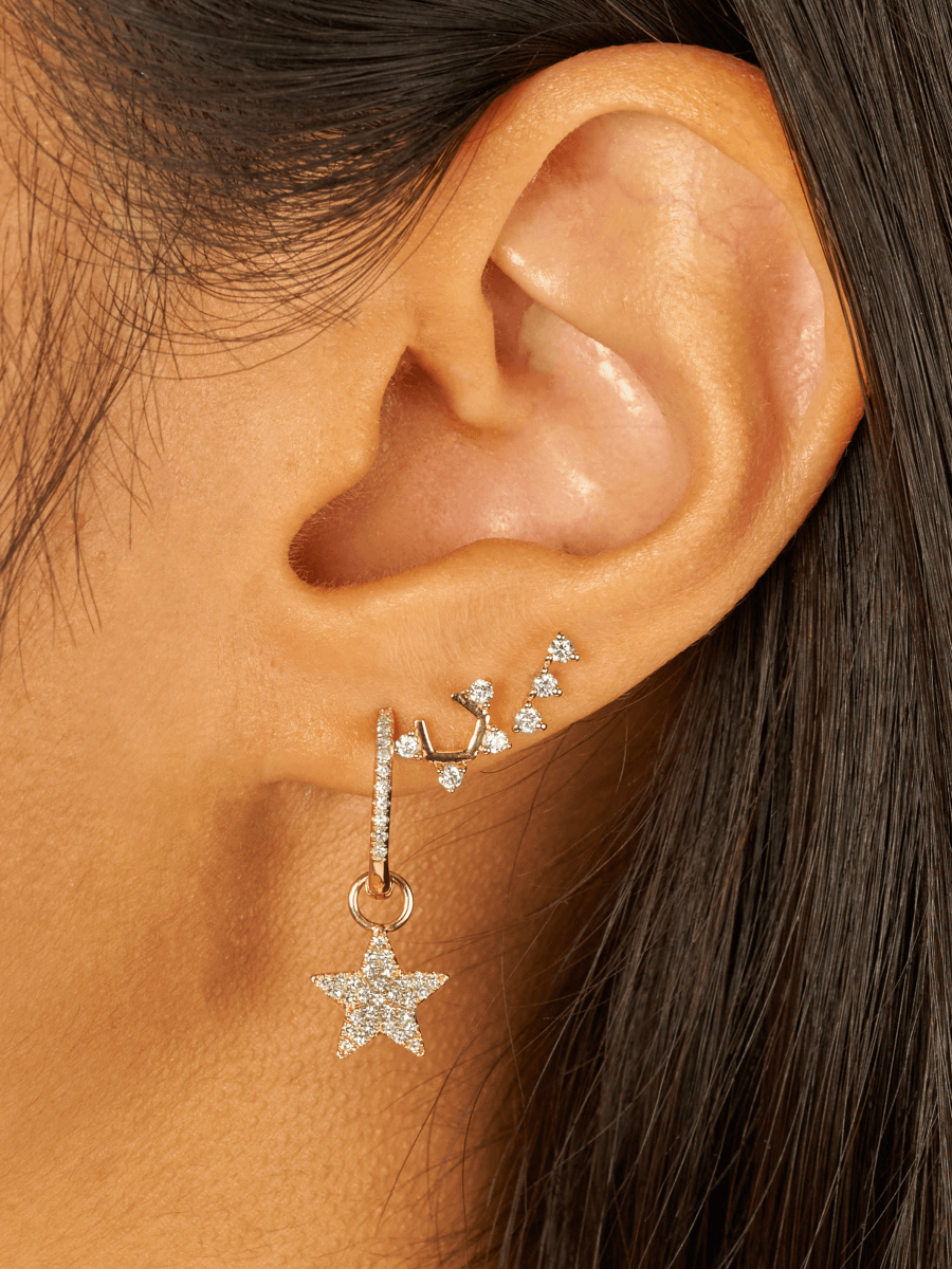 Three stone diamond earring paired with u shaped diamond earring and diamond star huggie