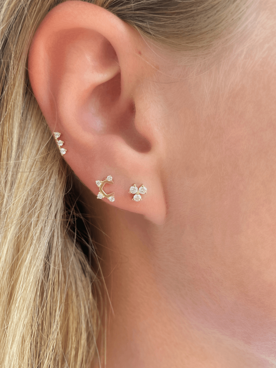 Three stone diamond earring paired with u shaped diamond stud and diamond trio stud