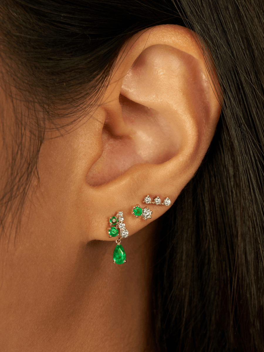 Three diamond earrings paired with emerald and diamond stud and emerald and diamond dangle stud 