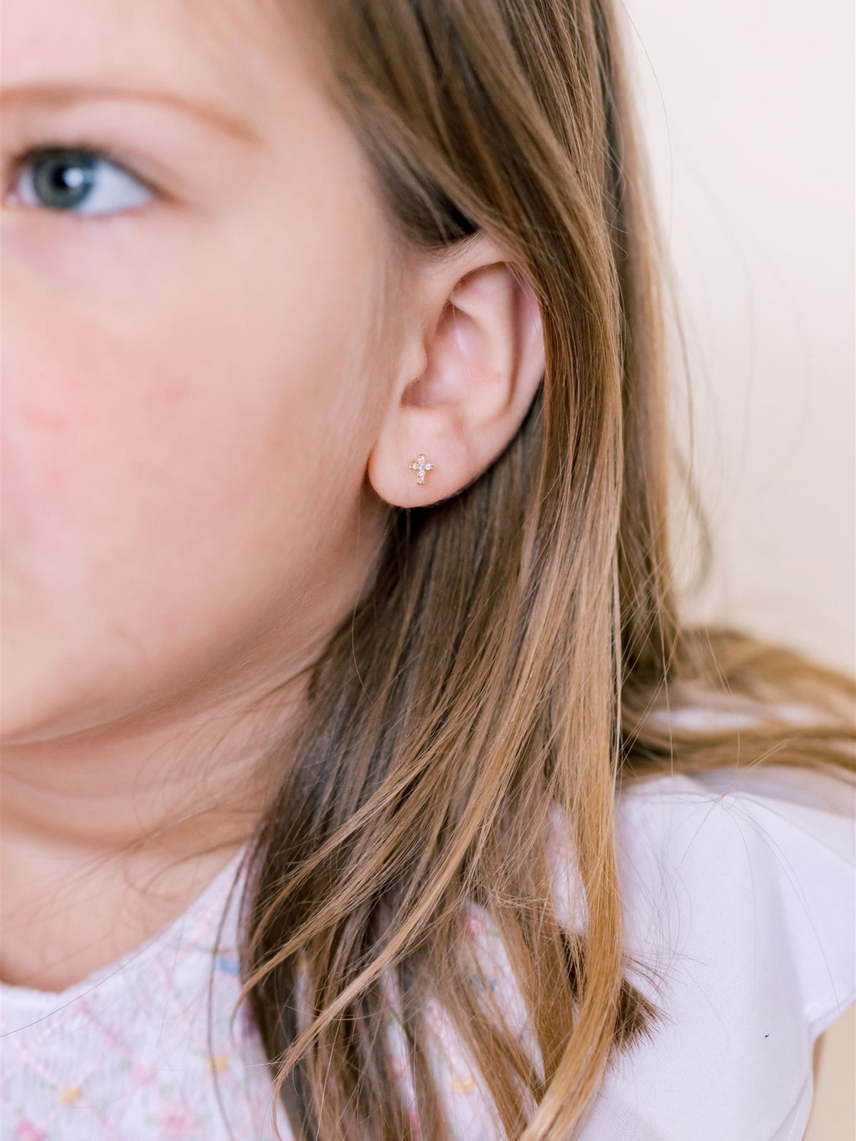 Mini Yellow Gold Diamond Cross Stud Earrings on Child's Ear