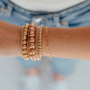 Everyday gold beaded stretch bracelets stacked with curb chain bracelet and gold paperclip chain bracelets on model wrist