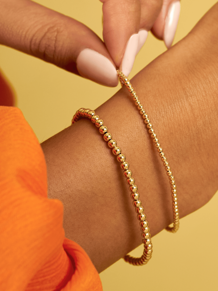 Gold bead stretch bracelets in different sizes on model wrist
