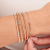 Small beaded stretch bracelets in silver and gold paired with mixed chain bracelet with diamond on model wrist