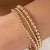 Gold small beaded stretch bracelets on model wrist