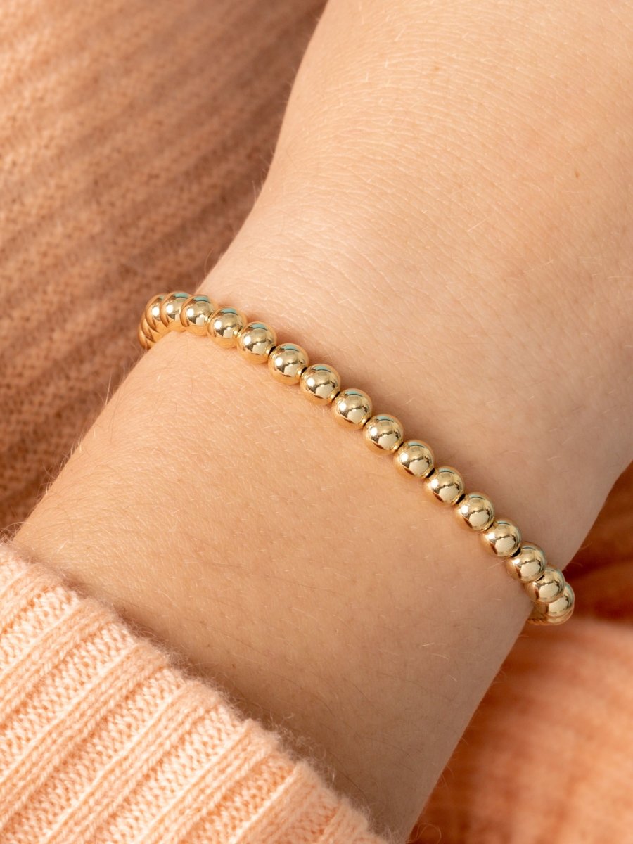 Yellow gold beaded stretch bracelet on model wrist