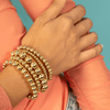 Gold beaded bracelets on model wrist