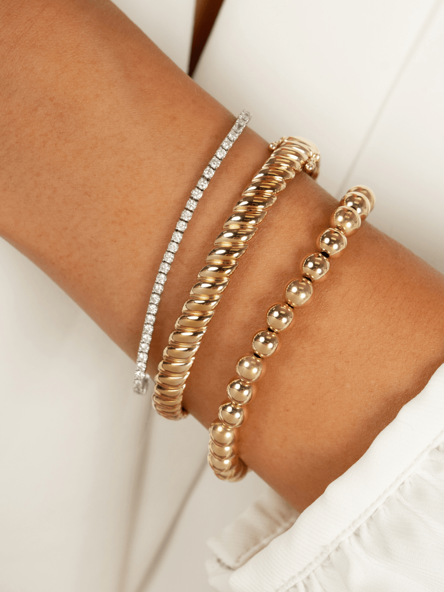 6mm gold beaded stretch bracelet stacked with diamond tennis bracelet and chunky gold bracelet on model wrist