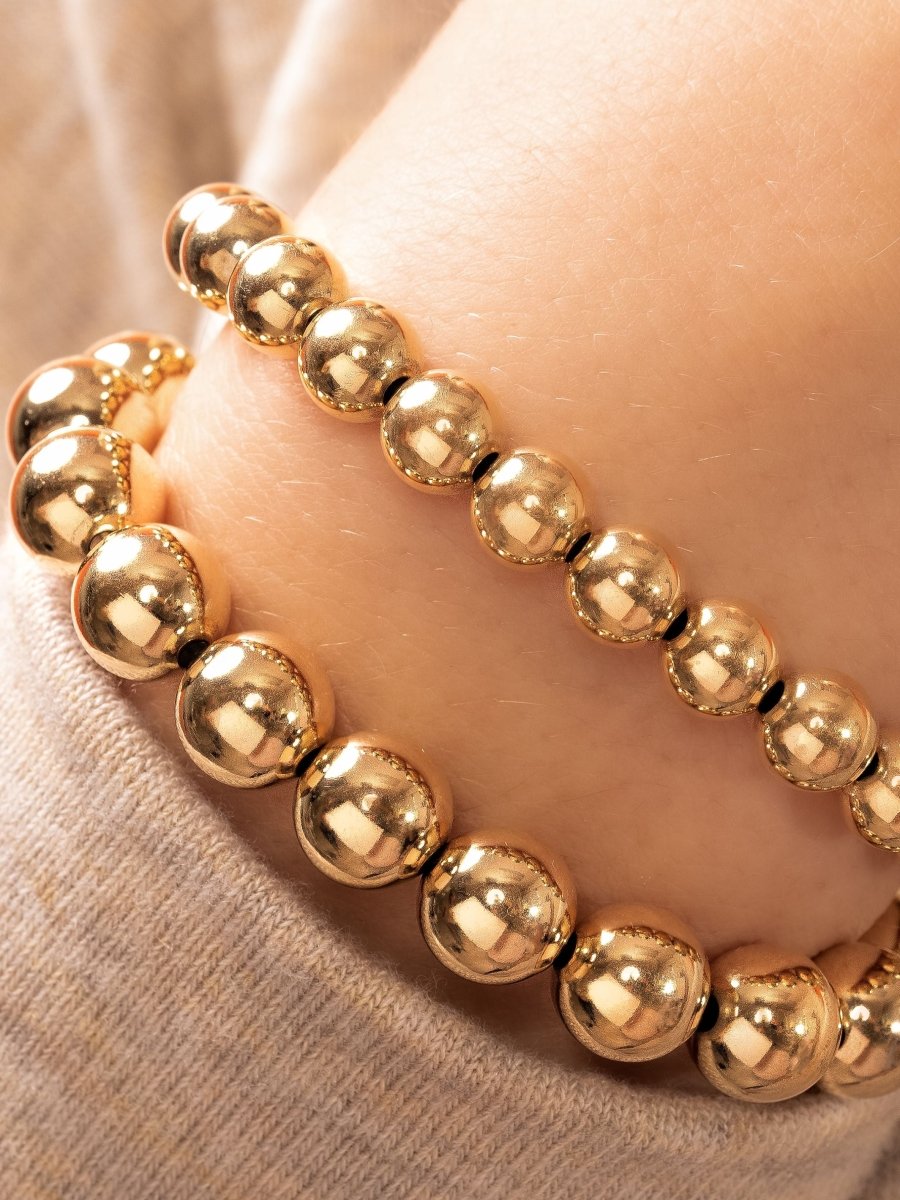 Gold beaded stretchy bracelets on model wrist