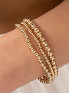 Gold stretch bracelet set 3mm, 4mm, and 5mm on model wrist