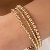 Gold stretch bracelet set 3mm, 4mm, and 5mm on model wrist