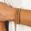Gold stretch bracelet set 3mm, 4mm, and 5mm on model wrist