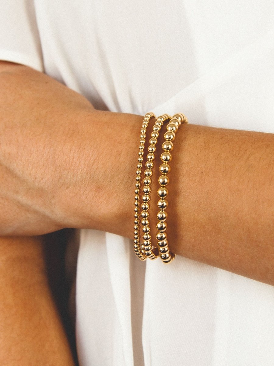Gold stretch bracelet set 3mm, 4mm, and 5mm on model wrist