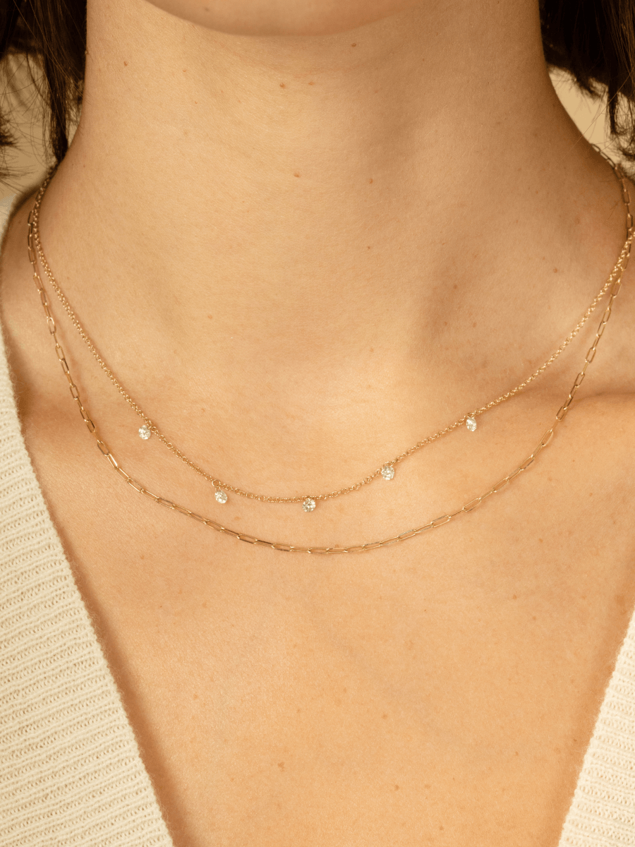 Hanging diamond necklace layered with thin gold paperclip chain