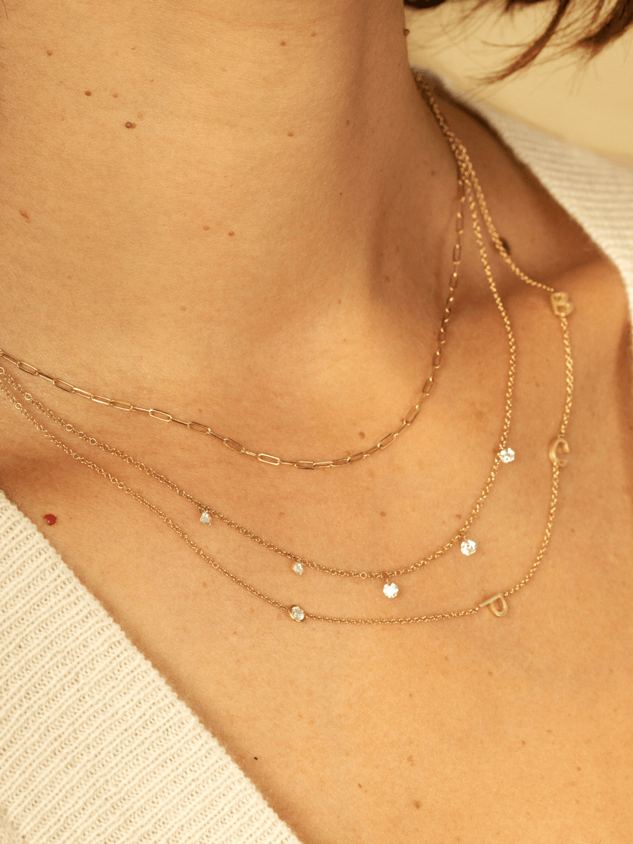 5 in 1 diamond necklace layered with gold paperclip chain necklace and gold initial necklace with single diamond
