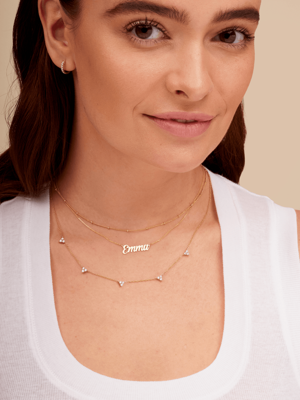 Gold script name necklace layered with trio triangle diamond necklace and satellite chain