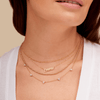 14K gold script name necklace layered with gold beaded necklace, trio triangle diamond necklace, and gold satellite chain