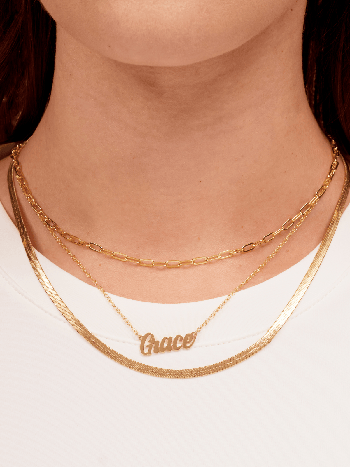 14K gold script name necklace layered with snake chain and gold paperclip chain