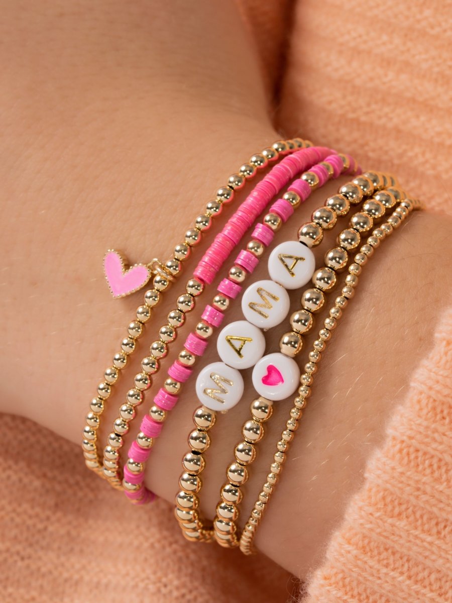 Pink heart stretch bracelet stacked with other pink and gold beaded stretch bracelets on model wrist