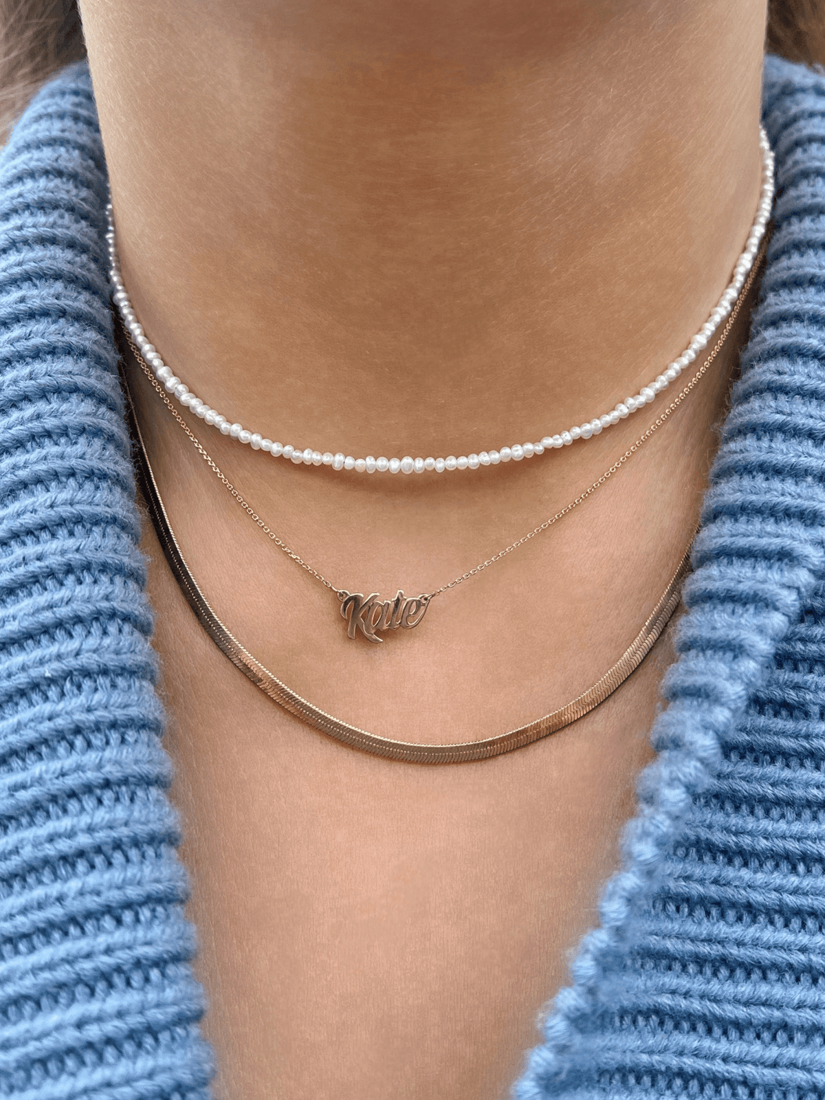 Gold snake chain layered with gold name necklace and pearl choker