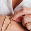 Initial bracelet with gold beads and gold charm paired with simple gold beaded bracelet on model wrist